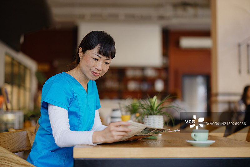 护士在咖啡馆放松，边喝咖啡边阅读杂志图片素材