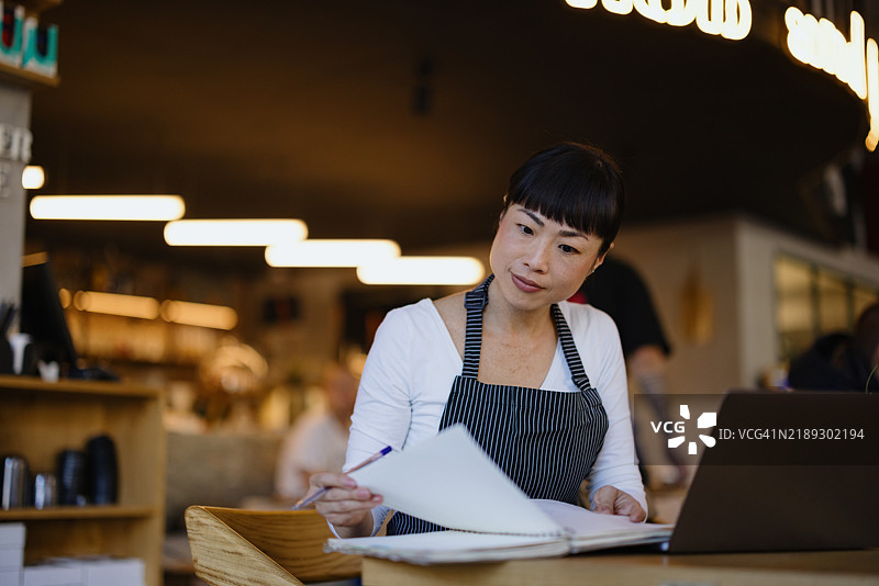 专注的咖啡师在舒适的咖啡店内审阅文件图片素材