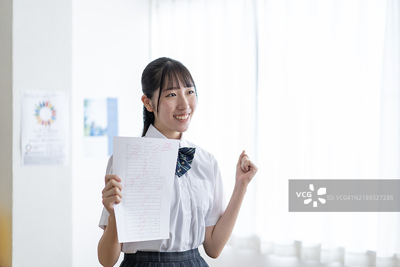 一名学生展示得分为100的考试成绩单图片素材