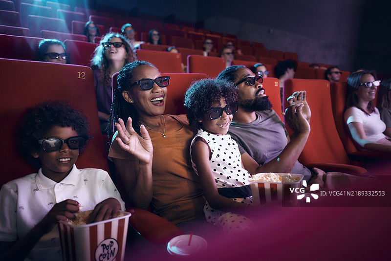 快乐的黑人家庭在电影院观看3D电影时享受乐趣。图片素材