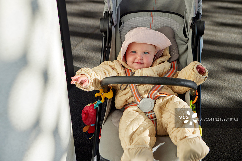 可爱的婴儿女孩穿着冬装在婴儿车里放松。图片素材