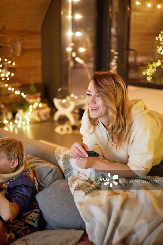 母亲和孩子在温馨的氛围中圣诞前夜观看电视图片素材