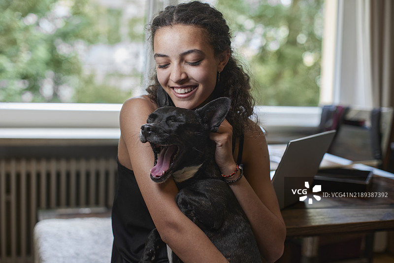 快乐的少女在家里抱着狗狗图片素材