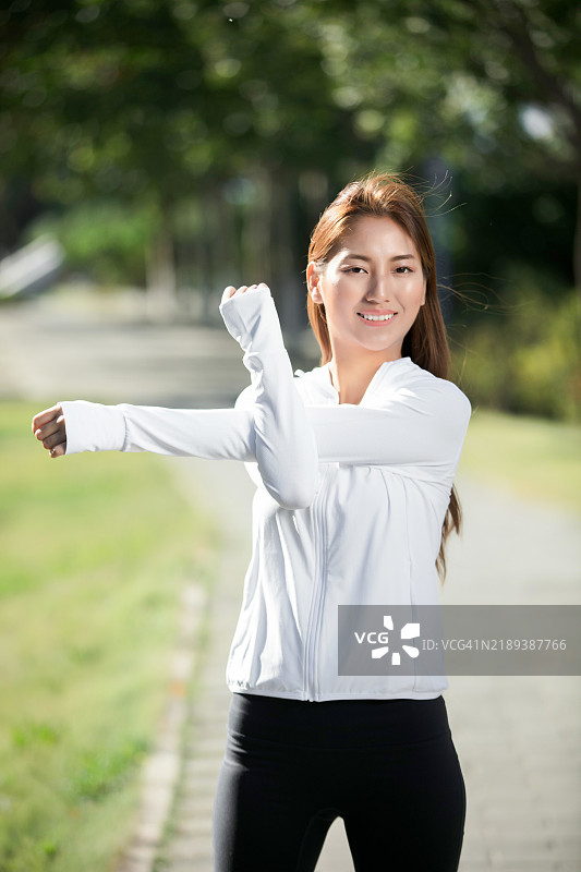 亚洲女性在公园里伸展手臂图片素材