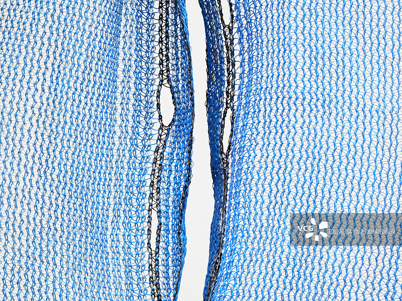 蓝色和黑色尼龙网的微距摄影。粗糙的纹理。色彩。阳光。图片素材