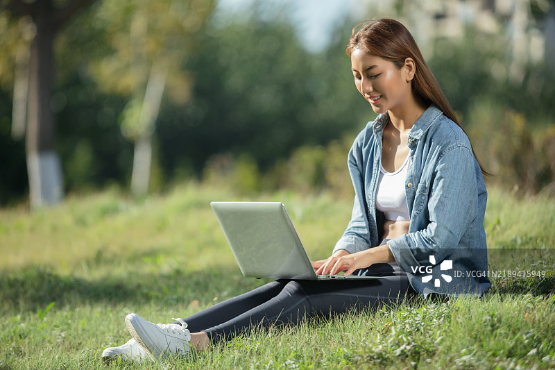 年轻的亚洲女性在户外使用笔记本电脑图片素材