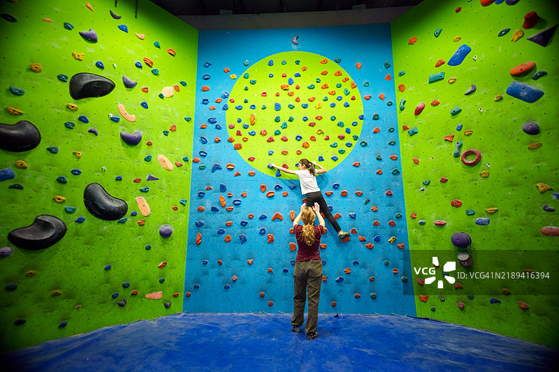 室内攀岩初学者 - 两位年轻攀岩者在色彩斑斓的墙面上图片素材
