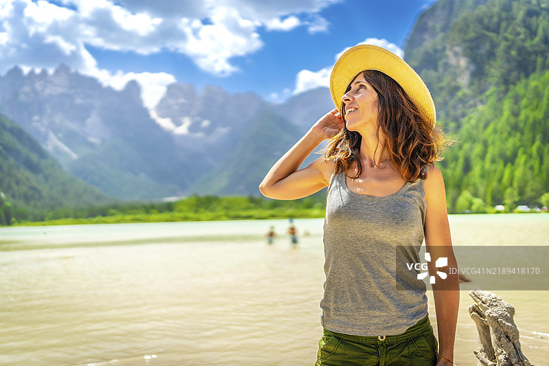 戴着草帽的游客欣赏着多洛米蒂山脉的壮丽景色，倒映在宁静的兰德罗湖水面上。图片素材