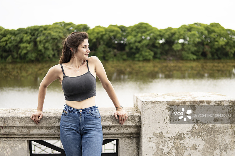 年轻女性站在海滨，侧目望去，神情迷茫。图片素材