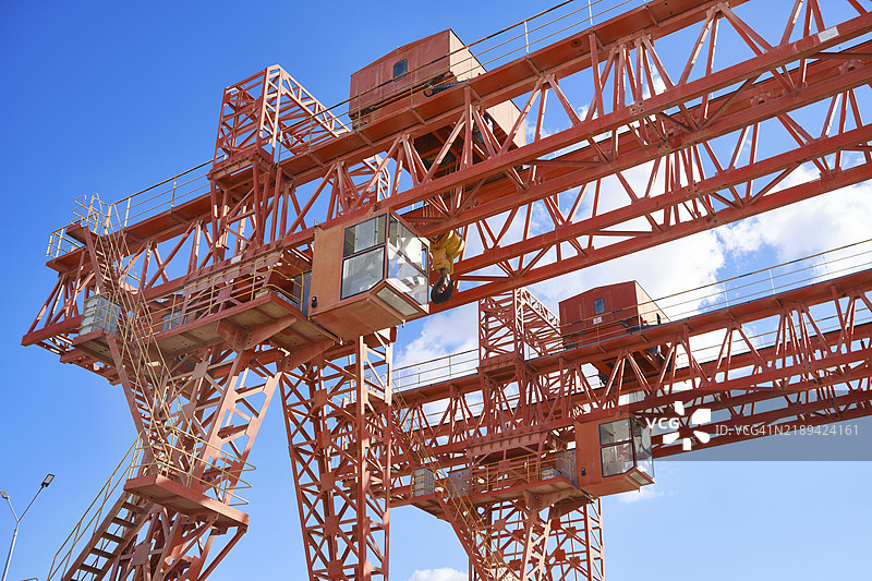 对面是多云天空的门式起重机。工业起重机械图片素材