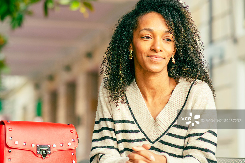 微笑的黑人女性坐在咖啡馆外的桌子旁图片素材