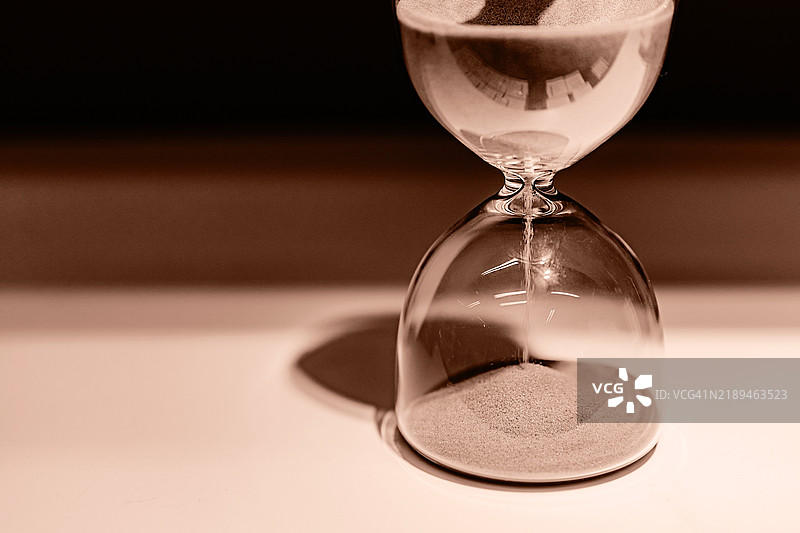 经典沙漏与流动的沙子在中性色背景上图片素材