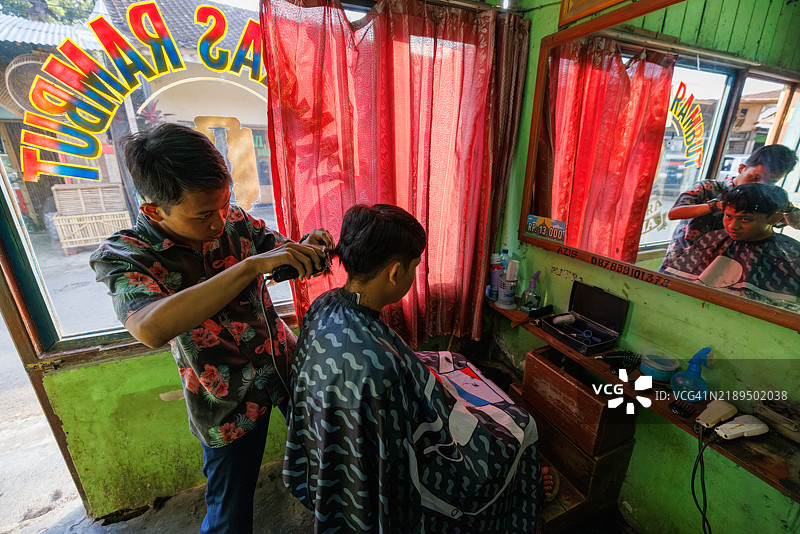 一位理发师在印度尼西亚中爪哇为顾客理发。图片素材