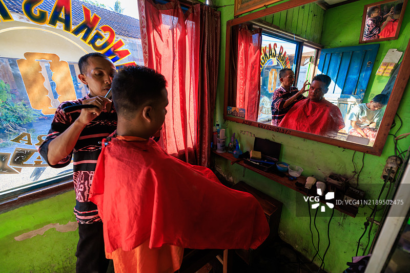 一名男子在印度尼西亚中爪哇的理发店理发和刮胡子。图片素材