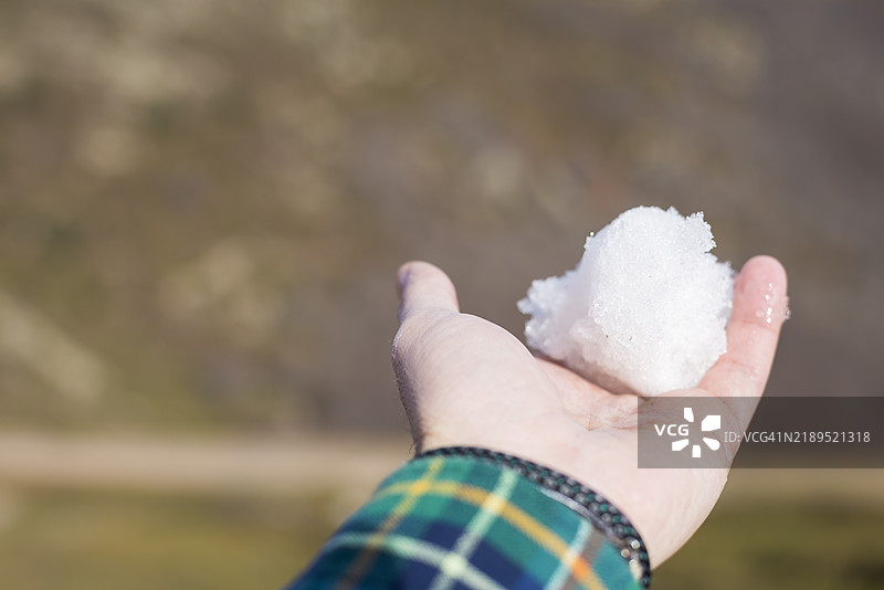 年轻男子手中握着一个小雪球。图片素材