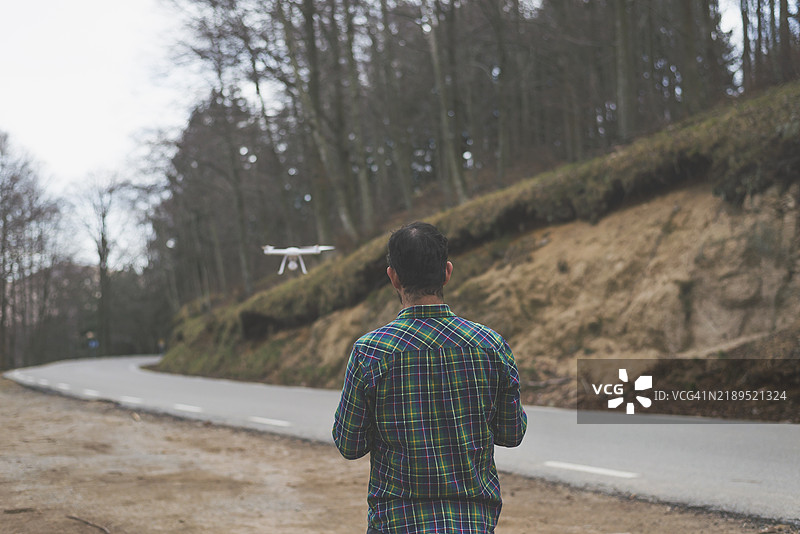 一名男子在山路旁使用无人机的背影图片素材