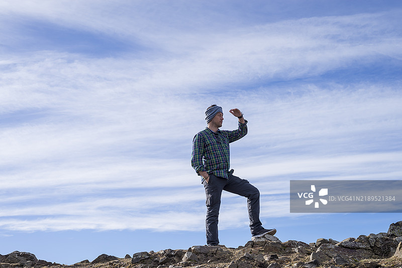站在山顶的男子戴着头带，享受着美丽的景色。图片素材