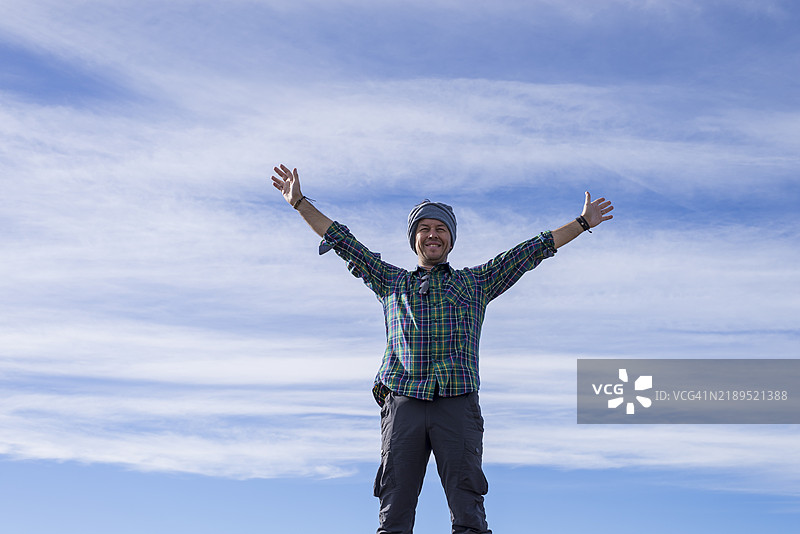 站在山顶的男子，戴着头带，举起双臂。图片素材