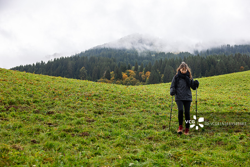 可爱的女性徒步旅行者在奥地利阿尔卑斯山的绿色山丘上漫游图片素材