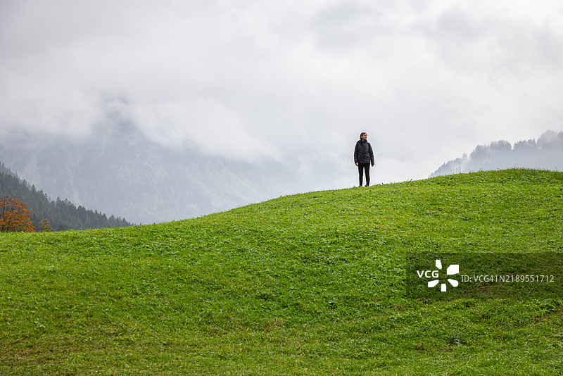 可爱的女性徒步旅行者在奥地利阿尔卑斯山的绿色山丘上漫游图片素材