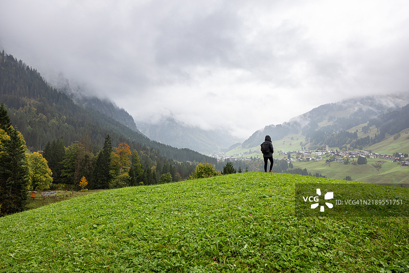 可爱的女性徒步旅行者在奥地利阿尔卑斯山的绿色山丘上漫游图片素材