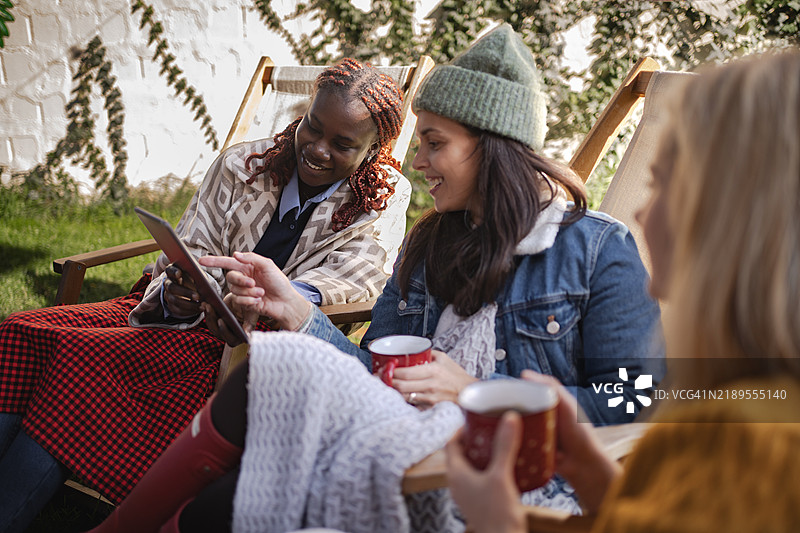 朋友们在后院使用平板电脑并喝热饮图片素材