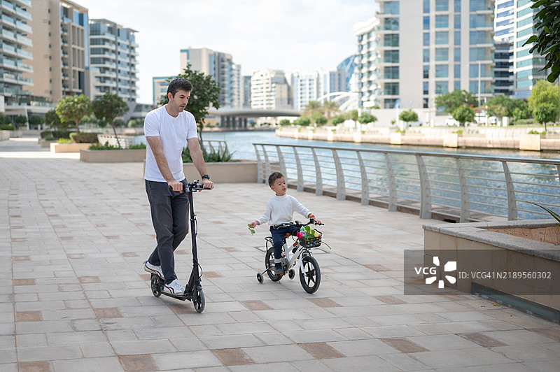 父亲和儿子在海滨骑滑板车图片素材