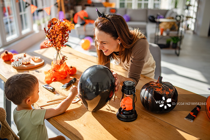 母亲和孩子在阳光明媚的家中一起制作万圣节装饰品图片素材