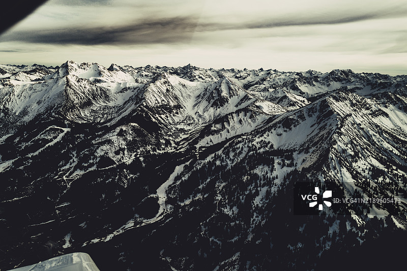 在奥地利蒂罗尔的莱赫谷上空飞行的小型飞机，晚冬时节的景象图片素材