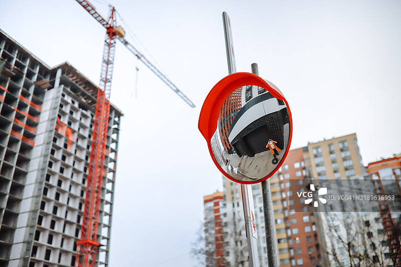 城市氛围：青少年在圆形镜子中的肖像，背景是建筑工地和起重机。图片素材