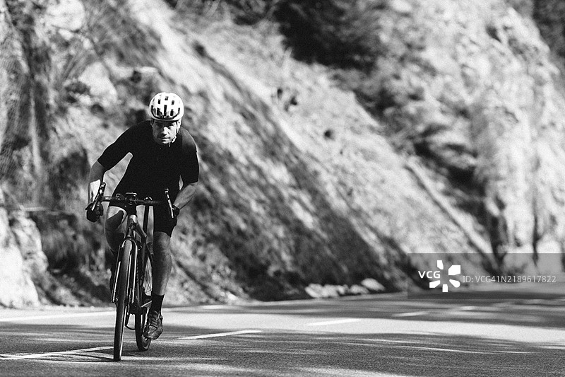 春季的公路自行车骑行者在奥地利蒂罗尔的莱赫塔尔和坦海默谷之间,背景是阿尔卑斯山的迷人风景。图片素材