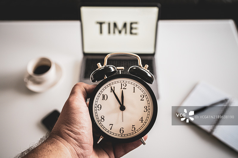 商务工作时间概念，笔记本电脑屏幕上的“时间”字样，办公桌上的笔记和时钟，工作压力，距离十二点还有五分钟的时钟图片素材