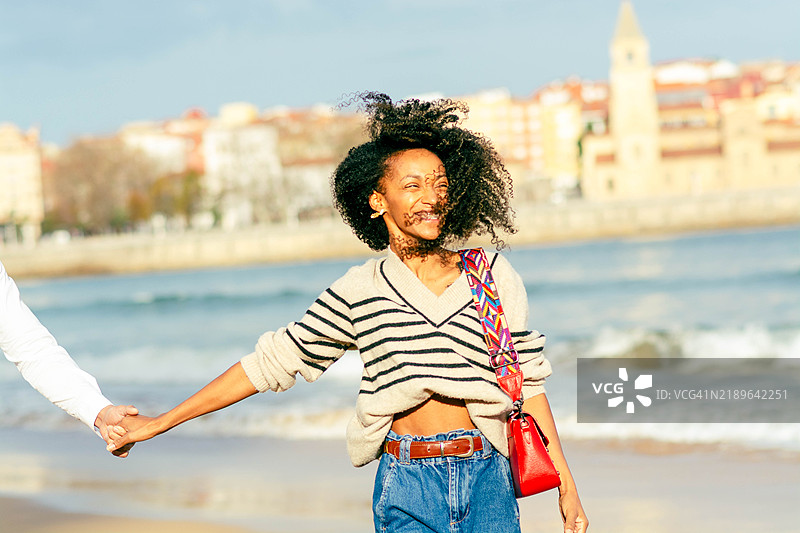 年轻女性牵着手在海滩上散步图片素材
