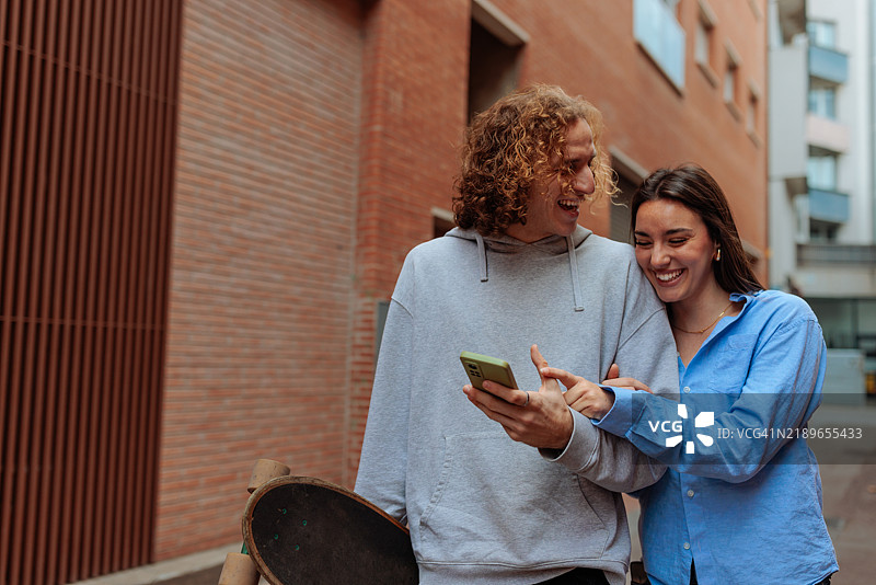 年轻的滑冰者们在智能手机上分享搞笑内容并一起大笑图片素材