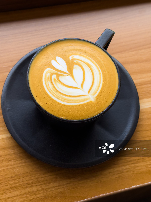 新鲜冲泡的拿铁咖啡放在木桌上图片素材