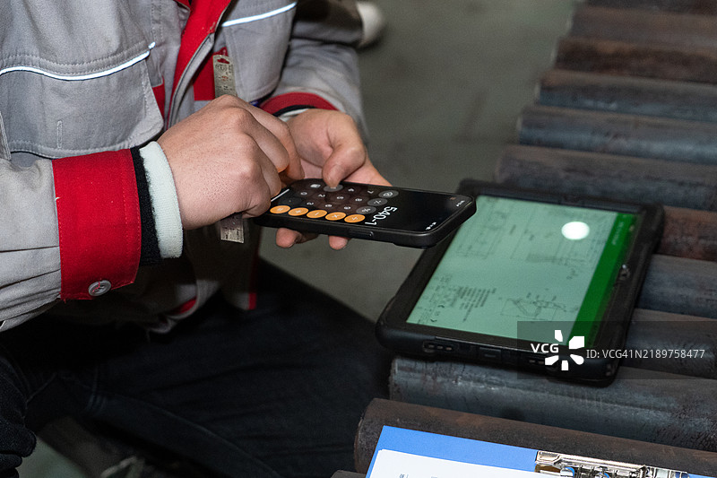工人在车间使用智能手机进行计算。图片素材