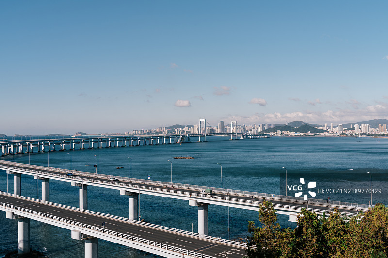 城市天际线、海洋的广阔以及蓝天白云下的跨海大桥图片素材