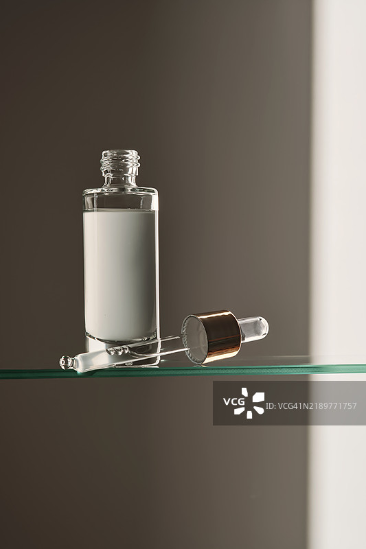 浴室玻璃架上的滴管面部精华液。图片素材