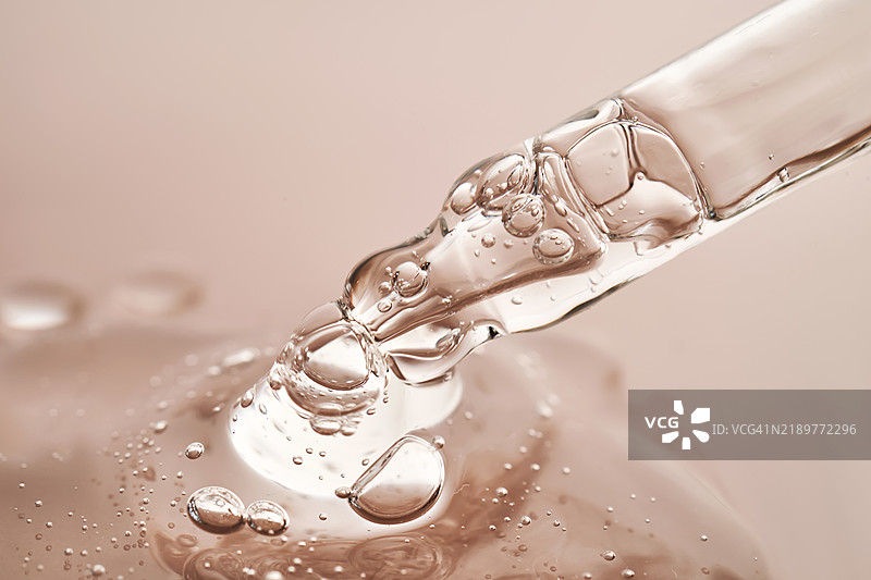 一支带有诱人滴液的移液管，背景为米色。图片素材