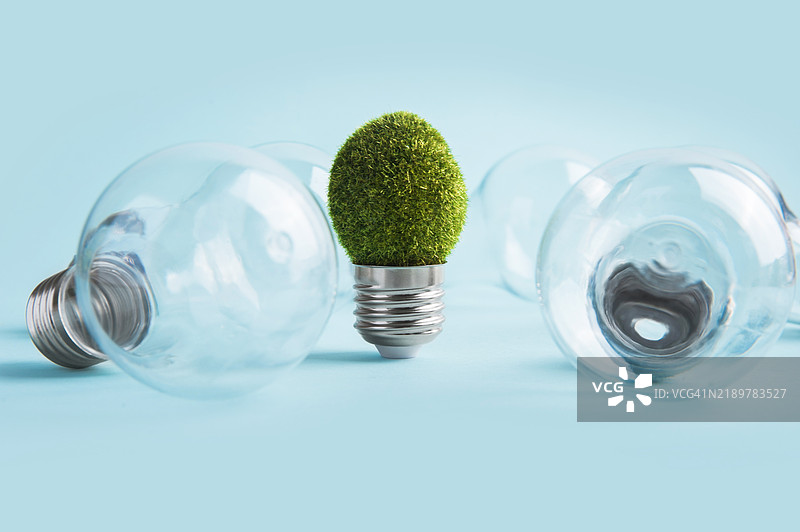 环保理念，蓝色背景上的绿色草地灯泡图片素材