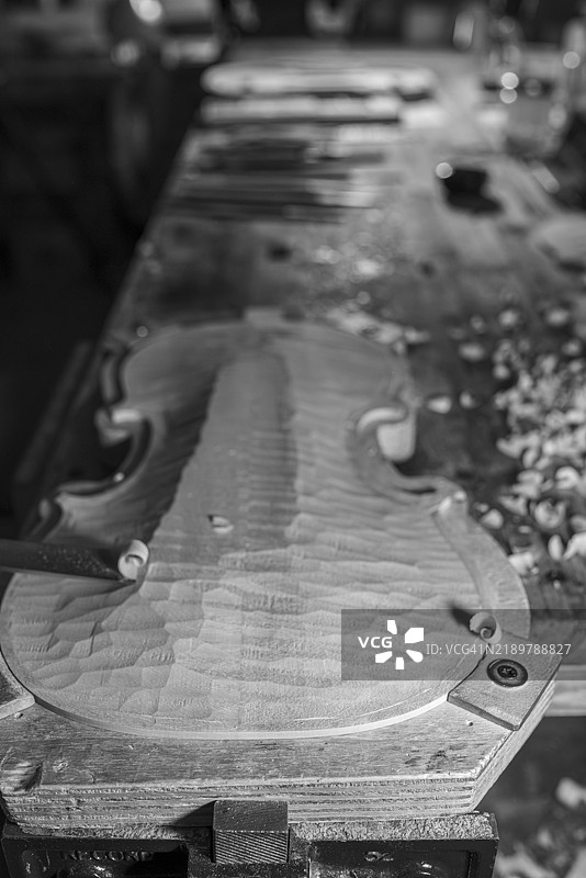 小提琴音板在工作室中被制琴师雕刻的特写，展示了工艺和木工技艺。图片素材