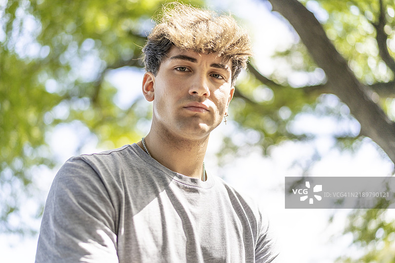 自信的年轻金发男子肖像，夏季树木背景图片素材