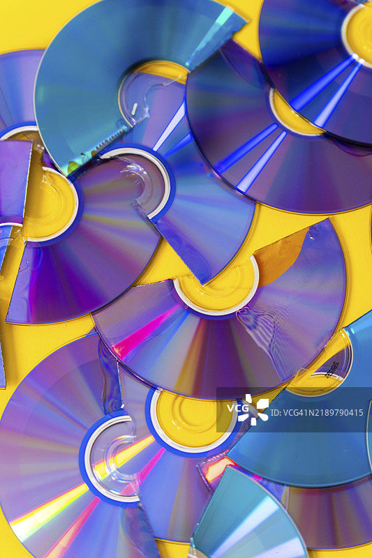 从上方看切割的光盘和DVD，背景为黄色图片素材
