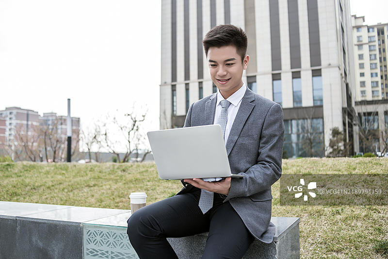 年轻的亚洲商人在户外使用笔记本电脑工作图片素材
