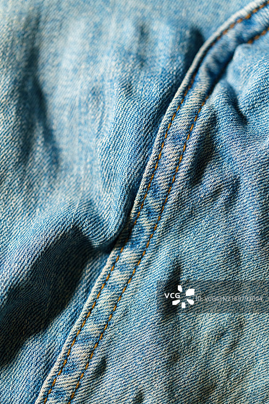 蓝色牛仔布料的纹理和缝合的细节特写，强调其复杂的结构。图片素材