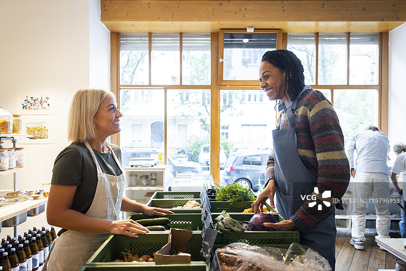 快乐的女性店主侧身站在箱子旁边交谈图片素材