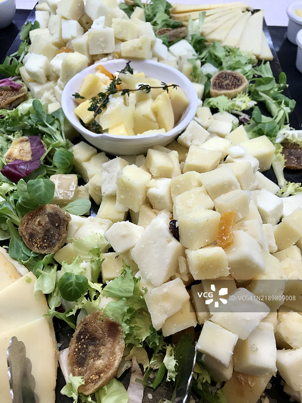切好的奶酪拼盘，搭配绿叶蔬菜和无花果图片素材