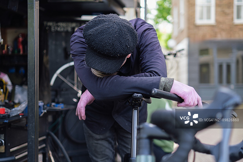 疲惫的自行车修理工在车间的车把上休息图片素材