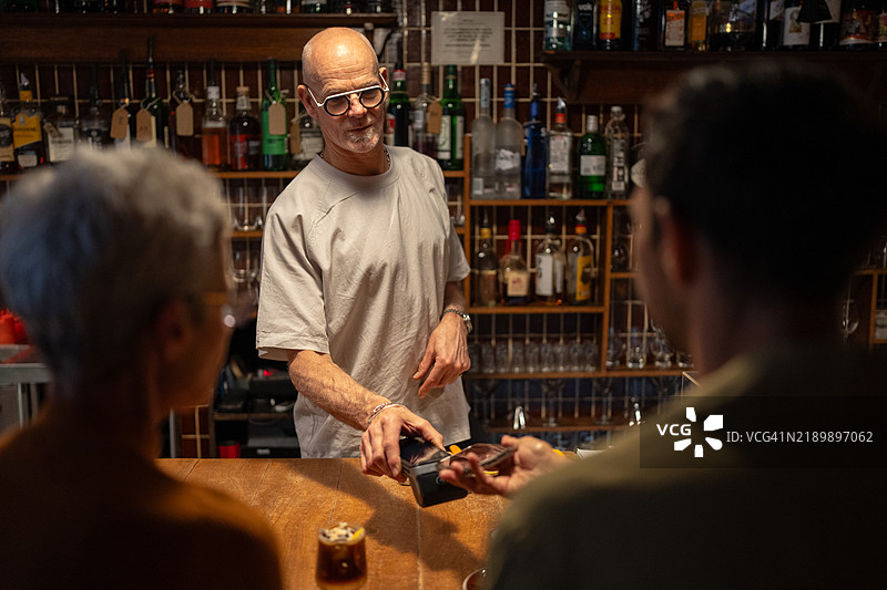 酒保在酒吧柜台处理无接触支付图片素材