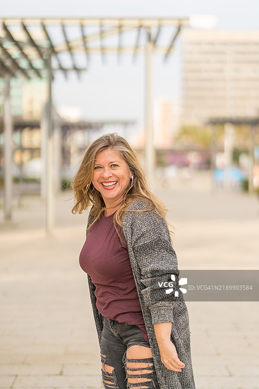 微笑的中年女性在城市公园散步图片素材